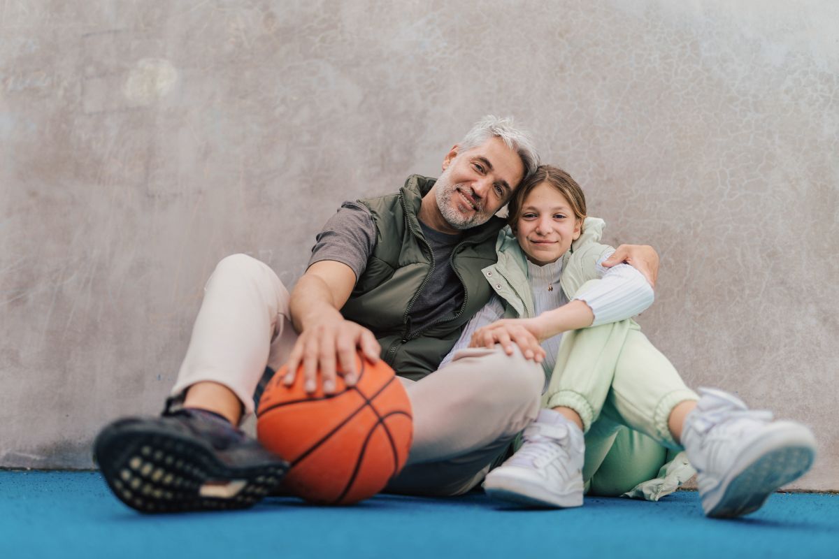 father and daughter sit with basketball